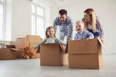Familia jugando con hijos pequeños dentro de cajas de cartón durante una mudanza