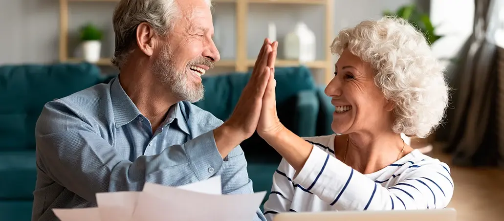 Pareja de adultos mayores sonriendo y chocando las manos en señal de celebración