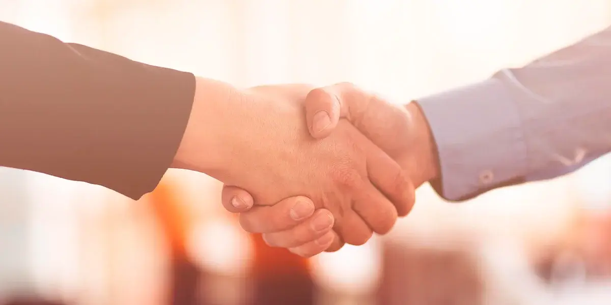 Primer plano de un apretón de manos entre dos personas, simbolizando acuerdo y confianza