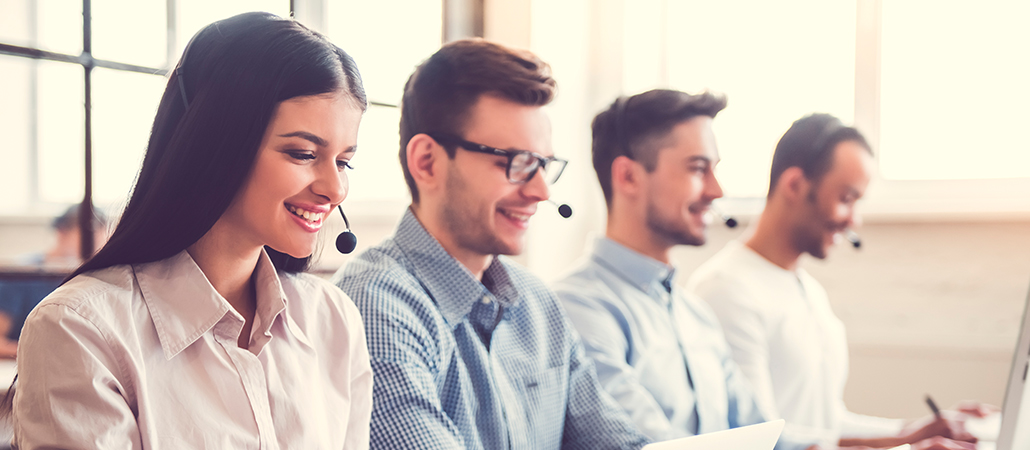 Grupo de agentes de servicio al cliente con auriculares trabajando en computadoras