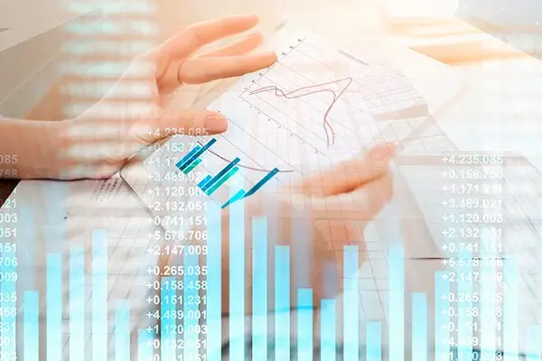 Mano sosteniendo hojas con gráficos financieros, con superposición de datos bursátiles y barras estadísticas en azul.