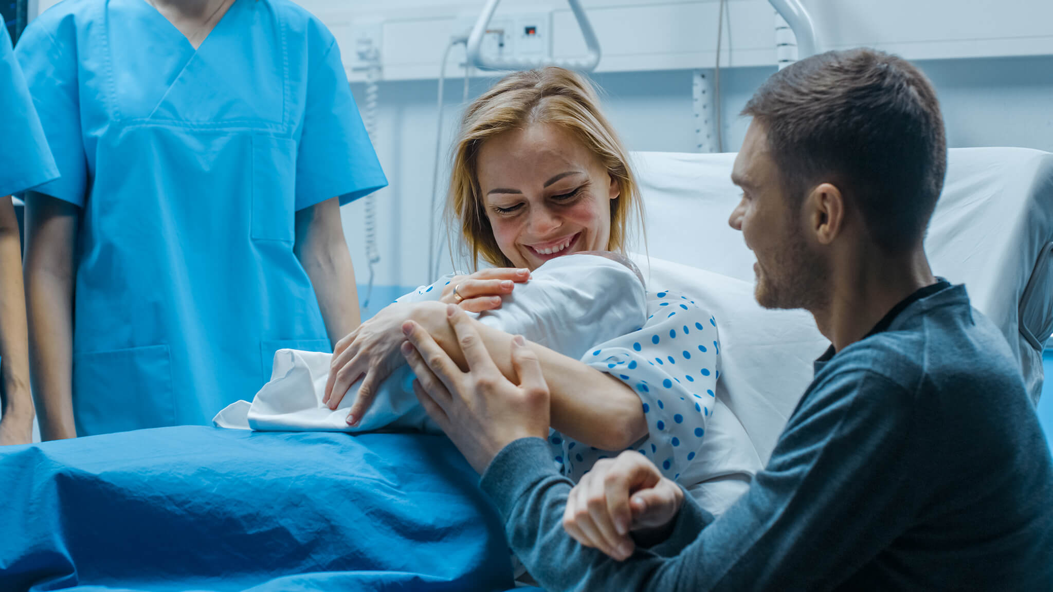 Pareja feliz sosteniendo a su recién nacido en una habitación de hospital.