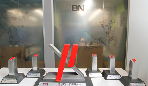 Premios y trofeos de BN Valores exhibidos en una mesa frente a un fondo con logotipo.